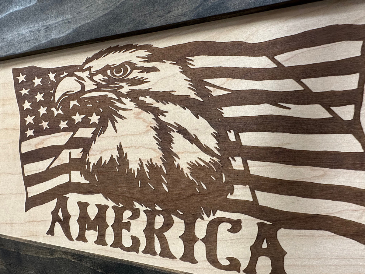Wood-engraved art piece featuring an American flag, bald eagle, and the text “AMERICA.”