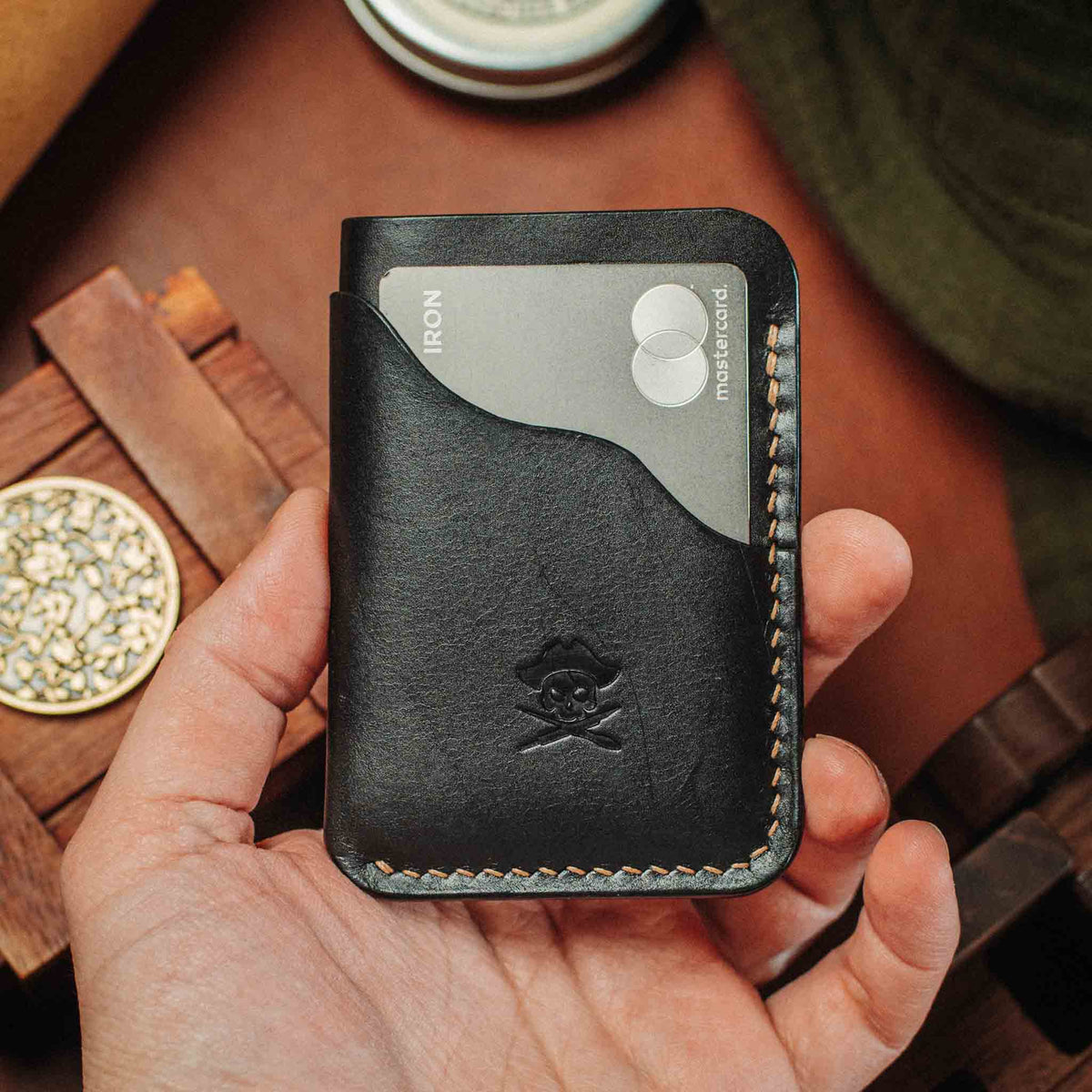Front view of the Venturer v2 slim wallet showcasing a black leather card holder, skull embossing, and contrasting stitching in a hand