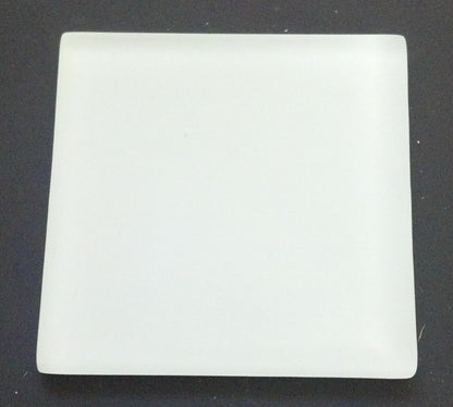 Top view of a white acid test scratch stone showcasing its smooth rectangular surface on a dark background
