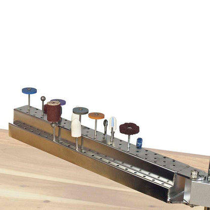 Angled view of Foredom bur holder arm accessory showing two tiers of holes with rotary tool accessories on a wooden workbench