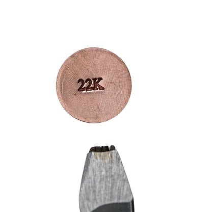 Close-up of hardened steel jeweler’s metal stamp showcasing a 22K hallmark impression on a white background