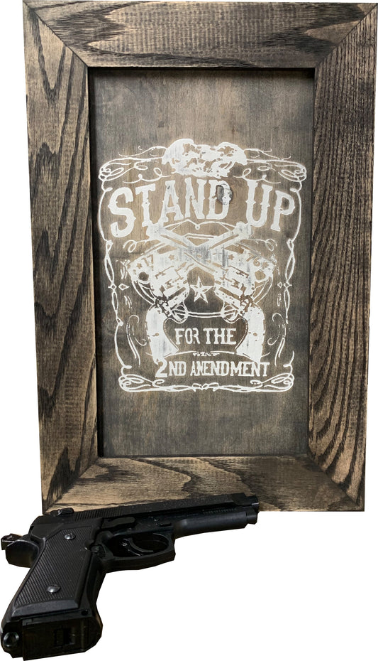 Dark gray wooden framed sign with white text "STAND UP FOR THE 2ND AMENDMENT" and crossed revolvers.