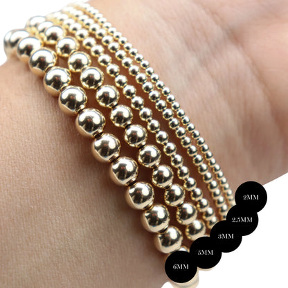 Gold beaded bands in 2mm, 2.5mm, 3mm, 5mm, and 6mm widths displayed on a wrist