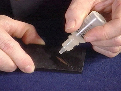 Gold testing acid applied to a scratched testing stone by hand