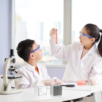 Scientist and child examine a test tube in a laboratory with a titanium cube displayed on the table