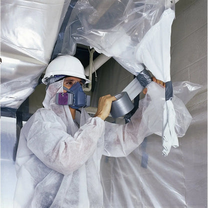 Worker in protective gear working inside a plastic containment enclosure