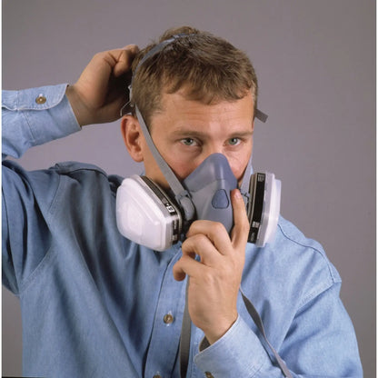 Front view of blue 3M 7500 Series Half Face Reusable Respirator showcasing side filters with a man adjusting the strap