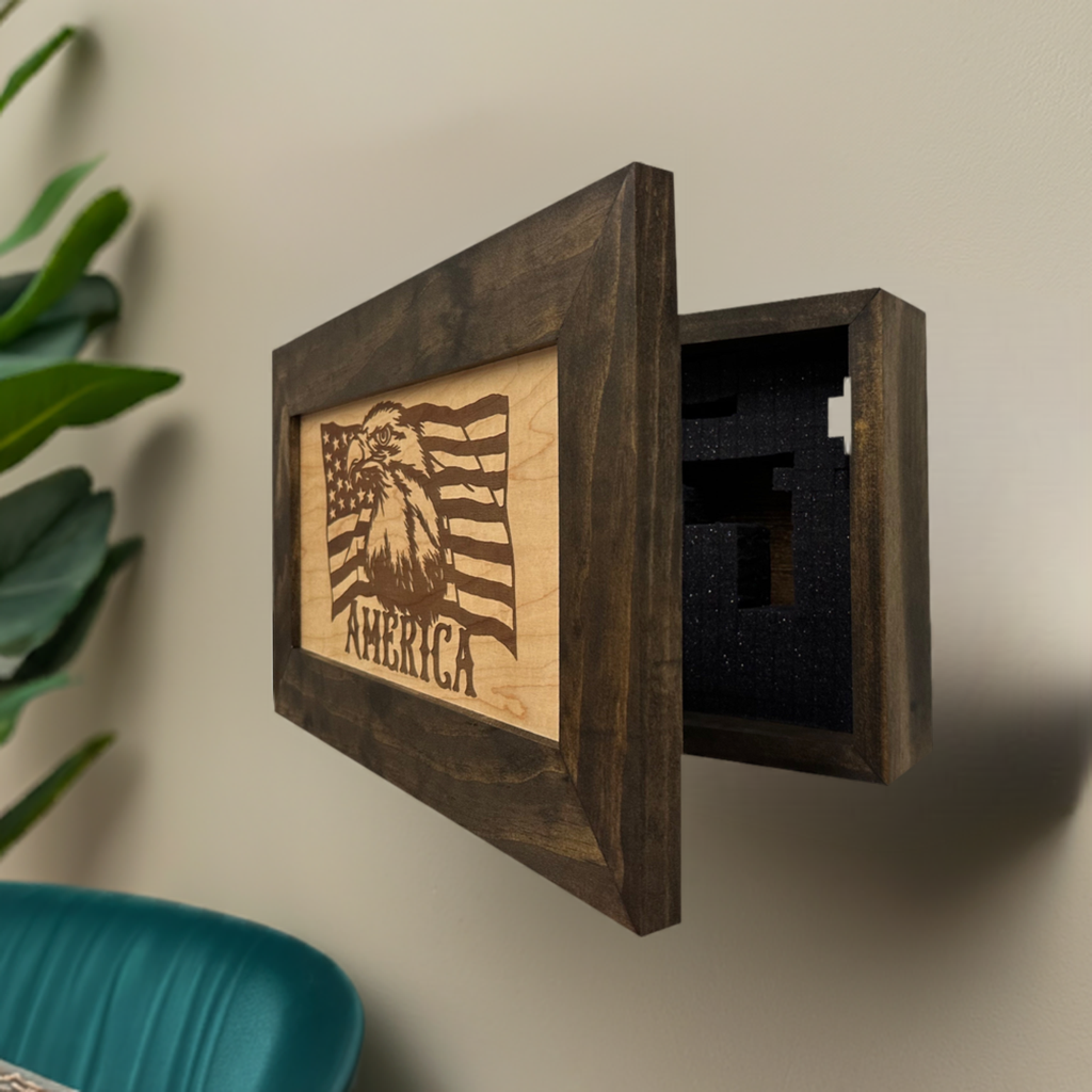 A dark wood wall safe with an American flag eagle design, open to reveal black foam interior.