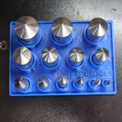 Front view of a blue center positioning die holder containing multiple circular metal dies on a dark surface