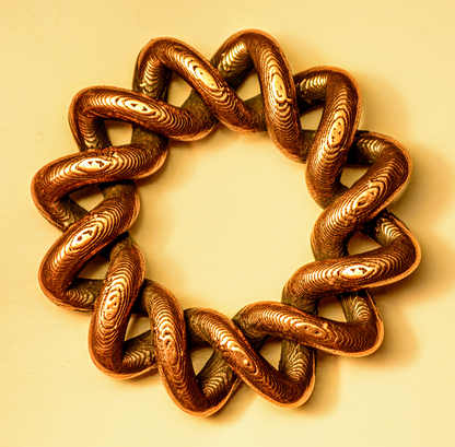 Top view of Copper Filamet showcasing twisted textured loops arranged in a circle on a pale background