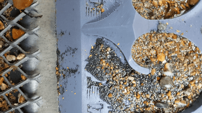 Close-up of 10X36 Sluice Mat, Dredge Dream Mat, showcasing a riffled surface holding gravel and gold-colored material