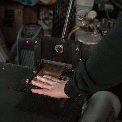 Front view of 6 inch Designer Series Guillotine Shear showcasing its cutting mechanism with a hand operating it on a workbench