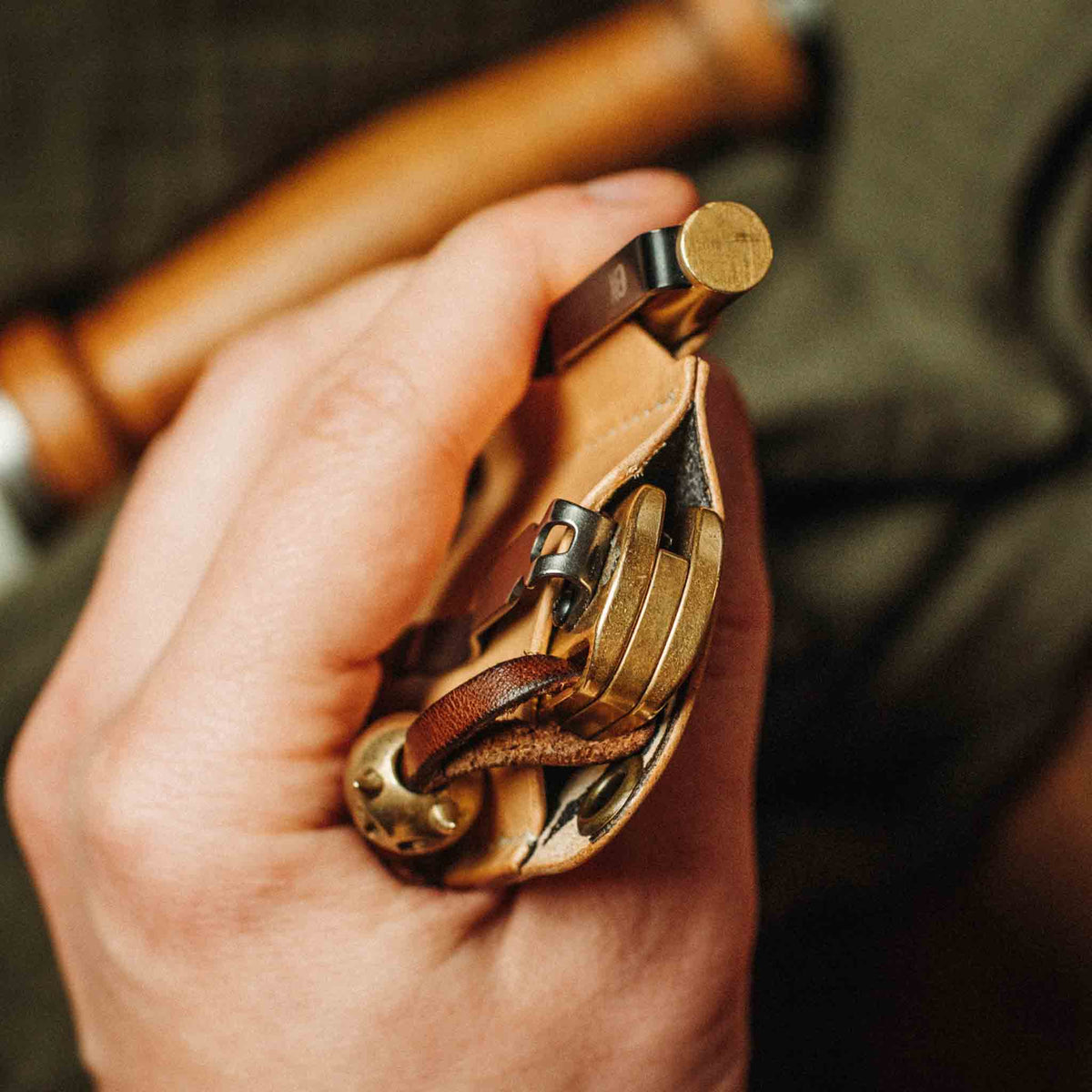 Close-up of the Sailor v3 leather EDC knife sheath showcasing a brass pocket knife and key ring in hand