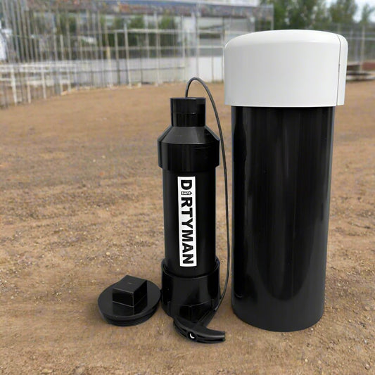 Black plastic "DIRTYMAN" hand pump and cylindrical container with white lid on dirt.