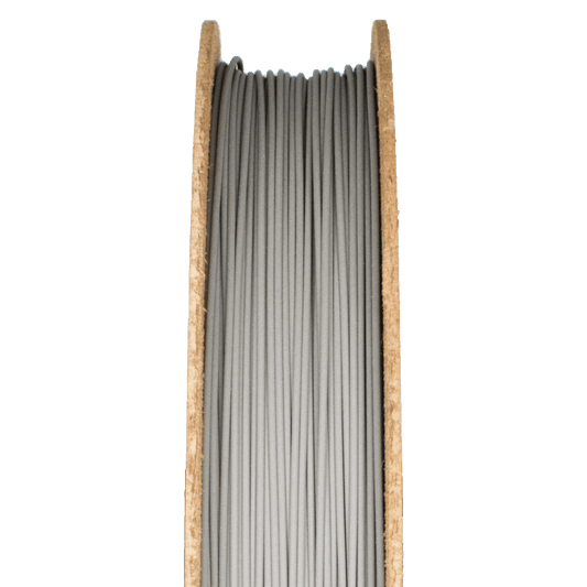 Close-up of M300 Tool Steel Filamet filament showcasing gray strands wound on a cardboard spool with a green background