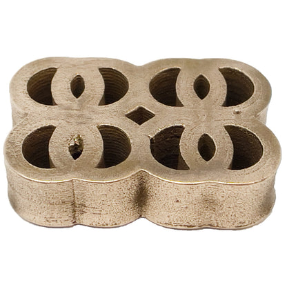 Gold-colored metal multi-purpose testing stone with ornate cutouts and a diamond shape in the center.