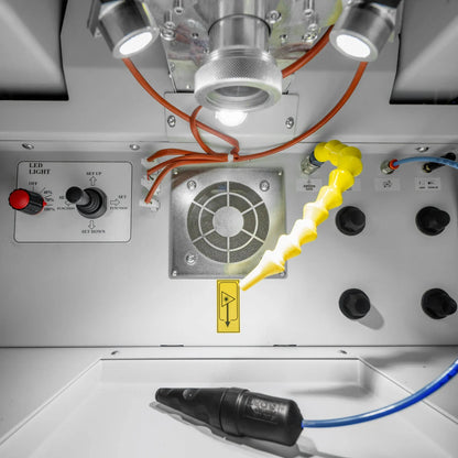 Interior view of Tauweld 225J benchtop laser welder showcasing LED lighting controls, ventilation fan, and yellow articulated hose