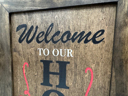 Close-up of wooden secure gun safe wall decor showcasing Welcome to Our Home lettering with a brown wooden frame