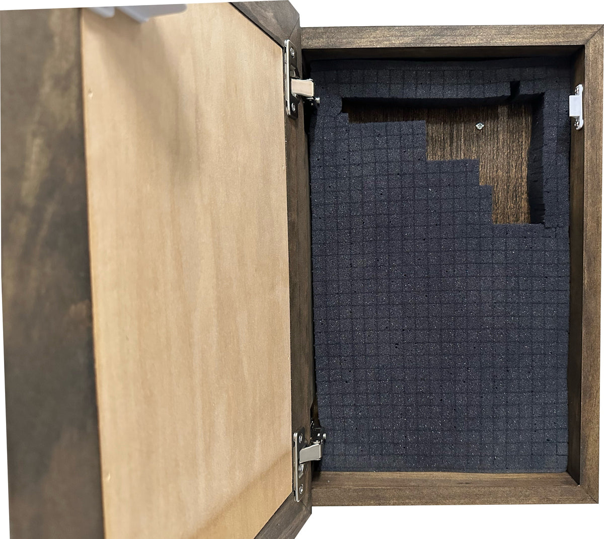 Open dark wood wall cabinet with hinged door, featuring dark grey grid-cut foam insert inside.
