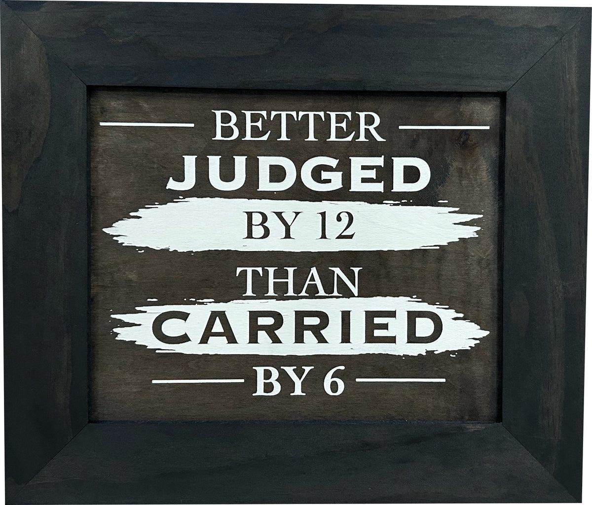 A dark wood-framed sign with white text reading "Better judged by 12 than carried by 6."