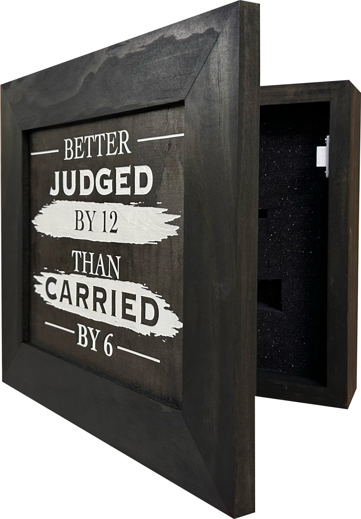 Dark wooden wall safe with text reading 'Better Judged By 12 Than Carried By 6' and foam interior.