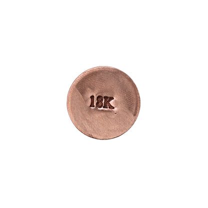 Close-up of a copper-colored metal sample stamped 18K for jewelers metal hallmarking