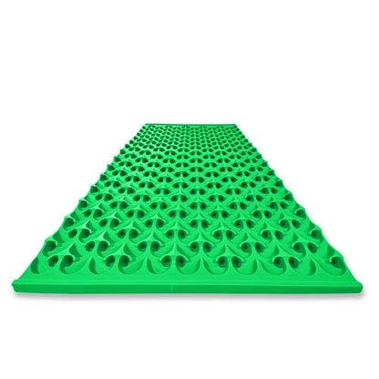 Angled view of 22 by 48 inch gold dredge Dream Mat showing its green textured surface with raised openings on white background