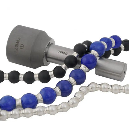 Close-up of FRETZ tube flaring tool for bead spacers marked TFM 2 beside blue, black, and silver beads on white background