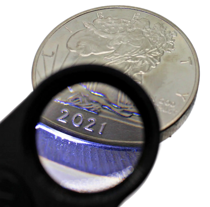Close-up of gold and silver jewelry acid test kit showcasing a magnifying loupe over a coin with a transparent background