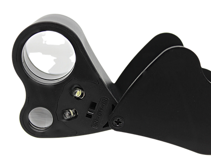 Close-up of LED eye loupe magnifier showcasing 30x and 60x lenses with black folding handle on a transparent background