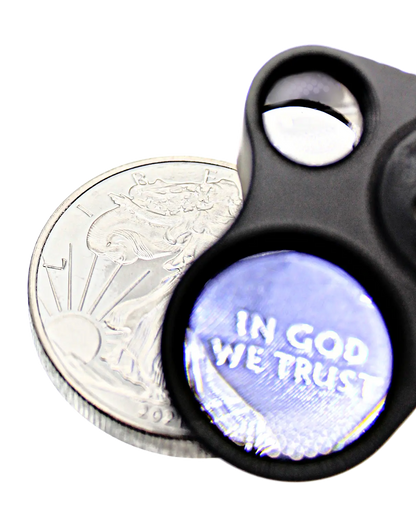 Close-up of 30x 60x LED eye loupe magnifier over a coin on a black background