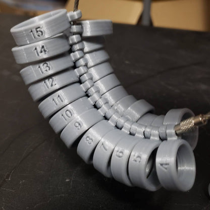 Close-up of SureFit 8mm comfort fit ring sizer set showing numbered sizes 4 through 15 on a connected chain
