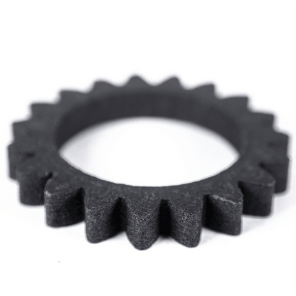 Angled view of High Carbon Iron Filamet showcasing a dark gear-shaped sample with toothed edges on a white background