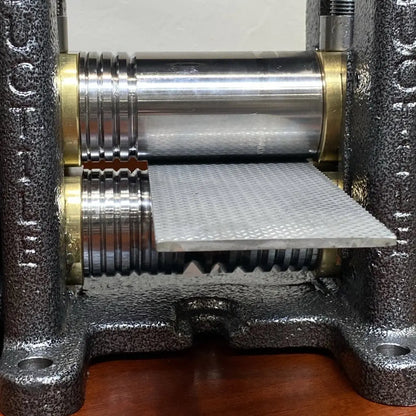 Close-up of Pepetools Triangle Mill showcasing metal rollers and a textured plate within its black cast-metal frame