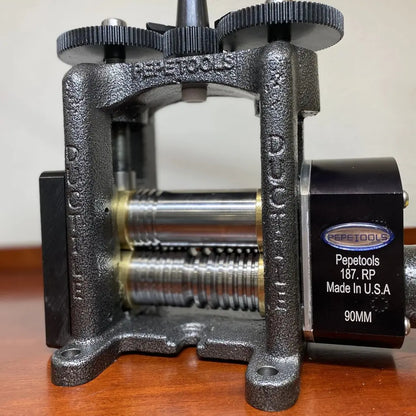 Front view of Pepetools Triangle Mill showcasing grooved rollers and geared adjustment wheels on a wooden table