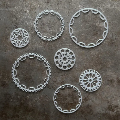 Top view of Tumble Wheels by Rosy Revolver and Jessica Jordan Cote set of 3 with circular openwork wheels and rings on a gray surface
