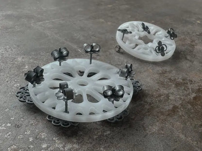 Close-up of Tumble Wheels set of 3 showcasing white perforated wheels with dark metal pieces on a gray surface