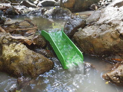 Angled view of green Mini Pocket Sluice Box with Dream Mat showcasing water flowing through it in a rocky stream