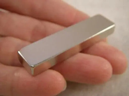 Close-up of a rectangular silver magnet held in a hand